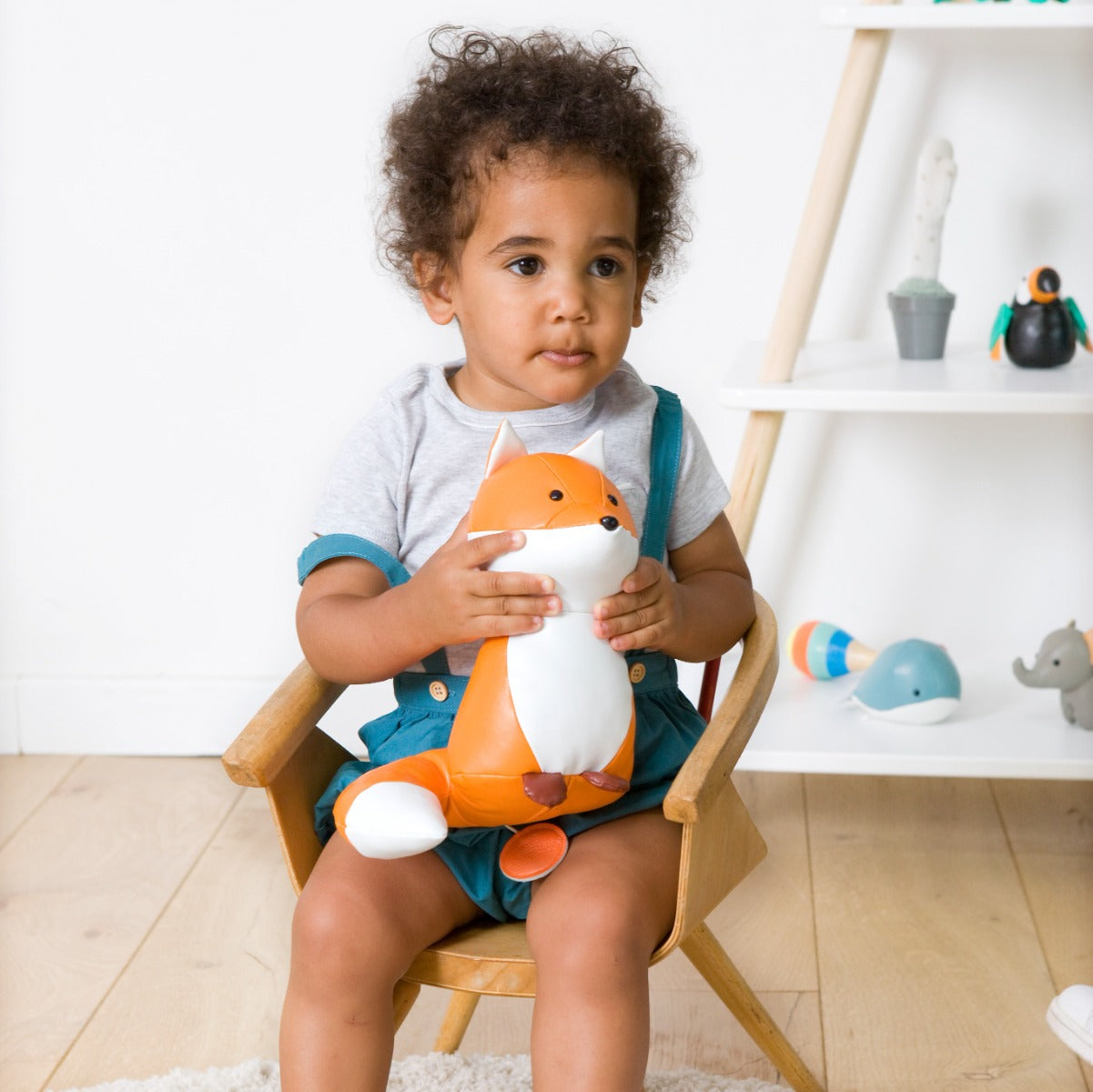 Baby boy holding Little big friends Richard the fox musical friend front view sitting in a chair