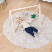 Baby playing with Wooden Activity gym lying on a rug