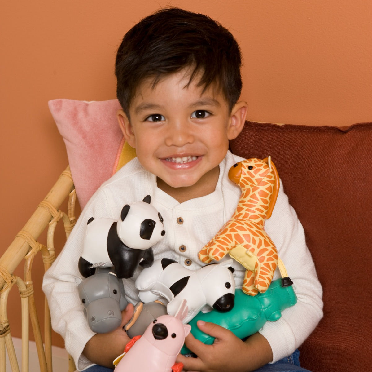 Baby boy holding all Little Big Friends Tiny Friends like cow, panda, giraffe