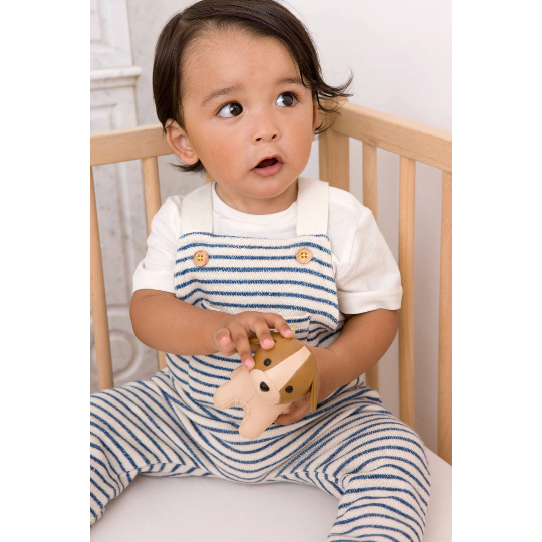 Baby boy holding Little Big Friends Tiny Friends Adrien the Dog sitting in a cot