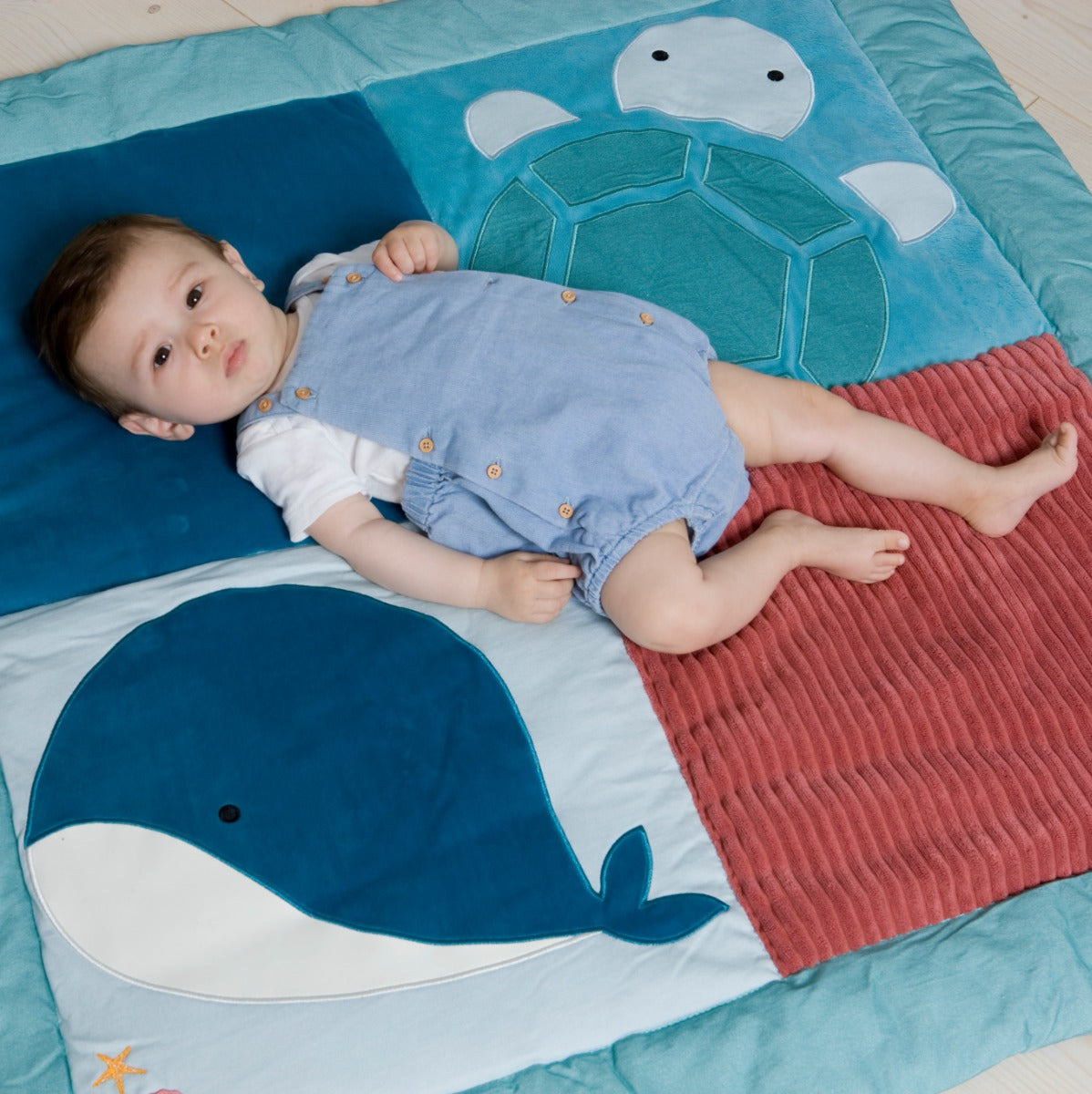 Baby lying on Reversible kids playmat in ocean print from Little Big friends