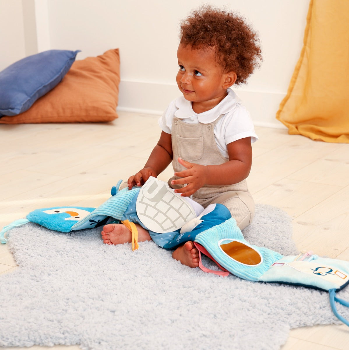 Girl holding Little Big Friends Activity Book in ocean sitting on a rug