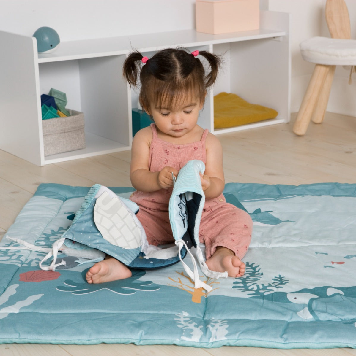 Girl playing with Little Big Friends Activity Book in ocean on a patchwork playmat