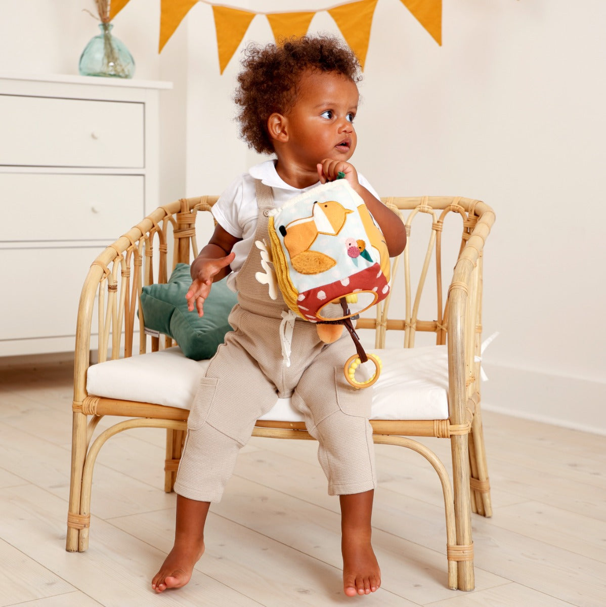 Kid holding Little Big Friends Soft Activity Cube Forest sitting on a chair
