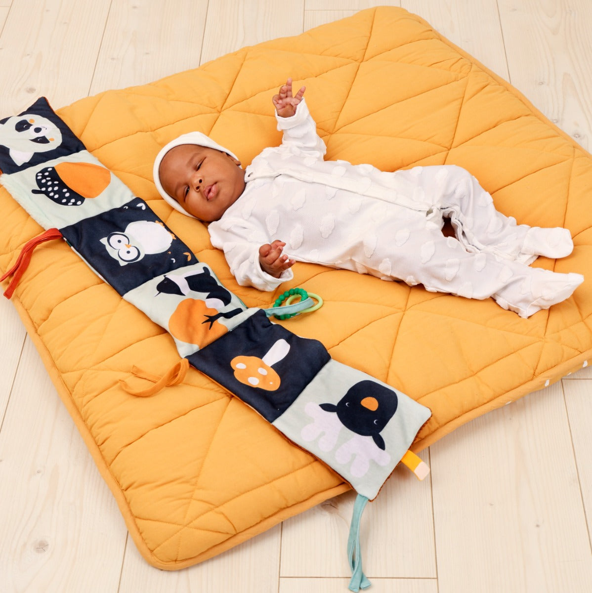 Baby sleeping on playmat besides Little Big Friends Activity Book in forest theme