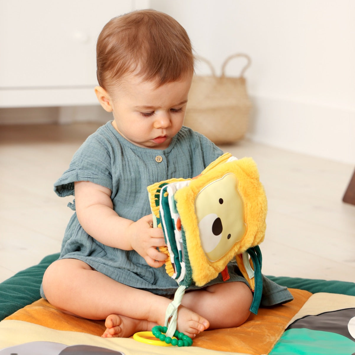 Baby girl playing with Little Big Friends Activity Book in jungle theme on a playmat