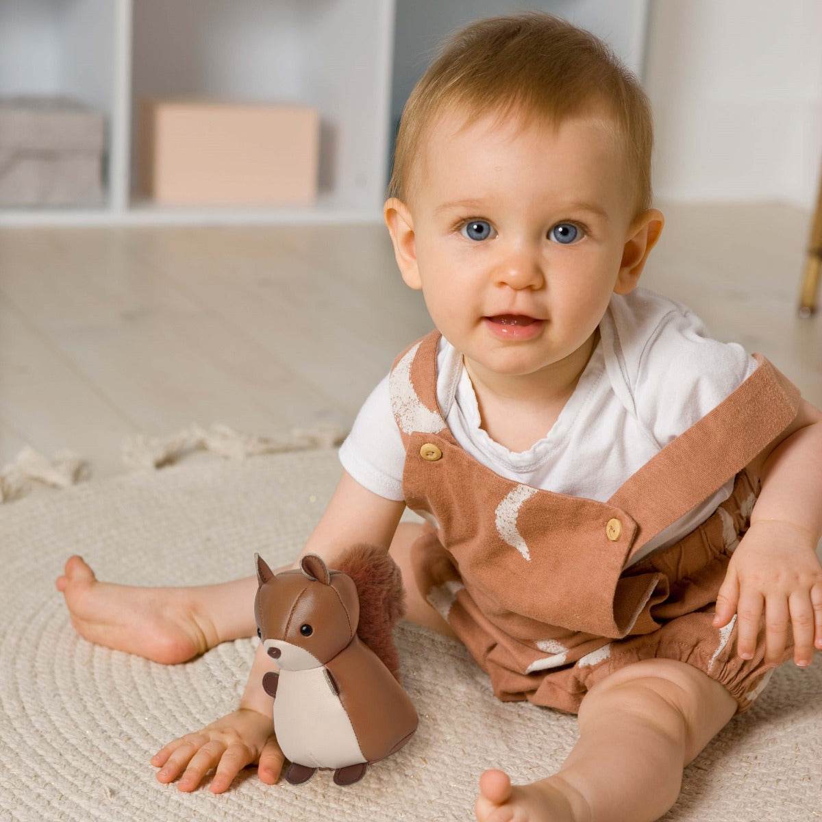 Baby boy playing with Tiny Squirrel Toy from Little Big Friends sitting on the floor