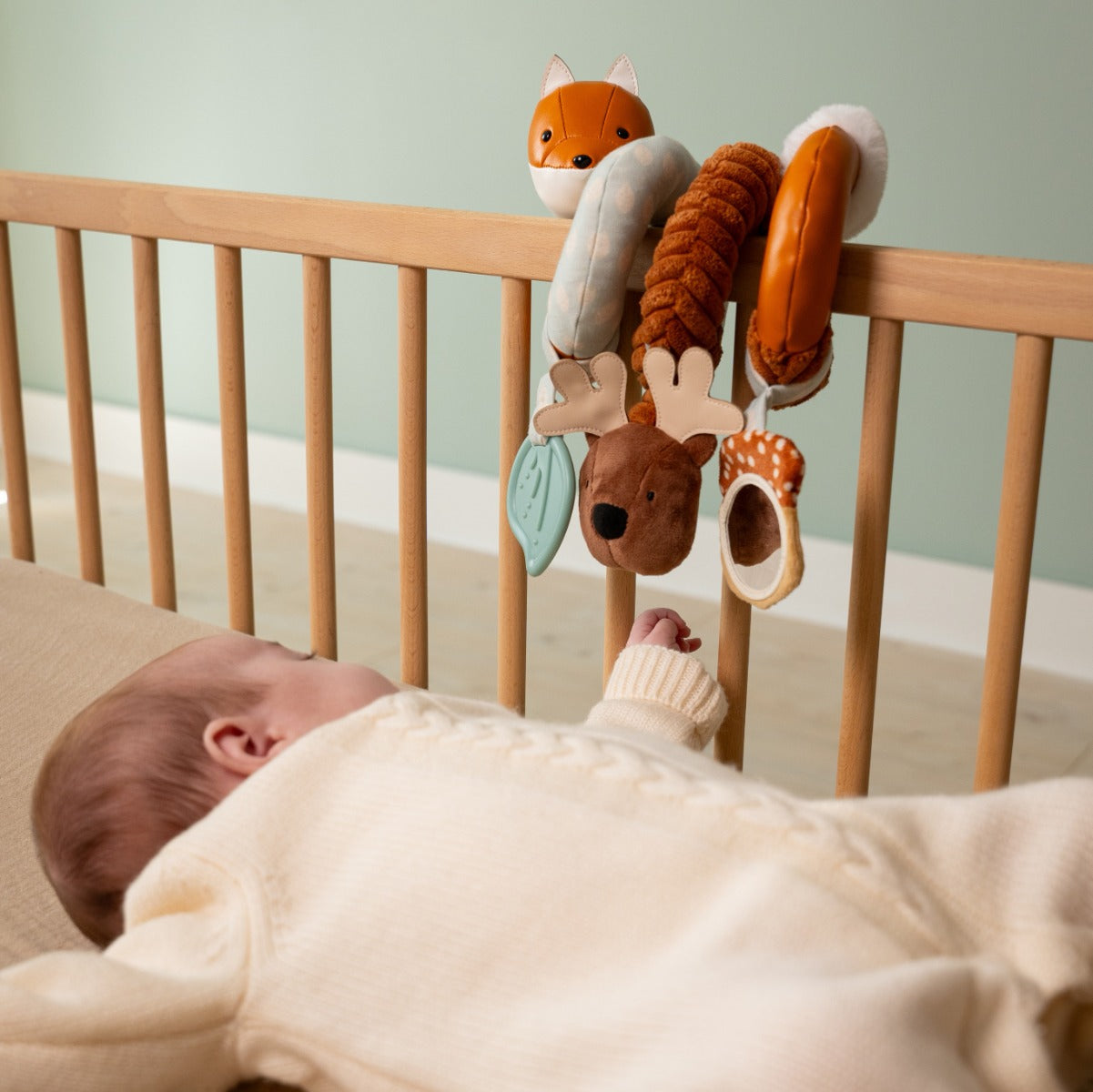 Baby in a cot playing with Activity Spiral - Forest from little big Friends