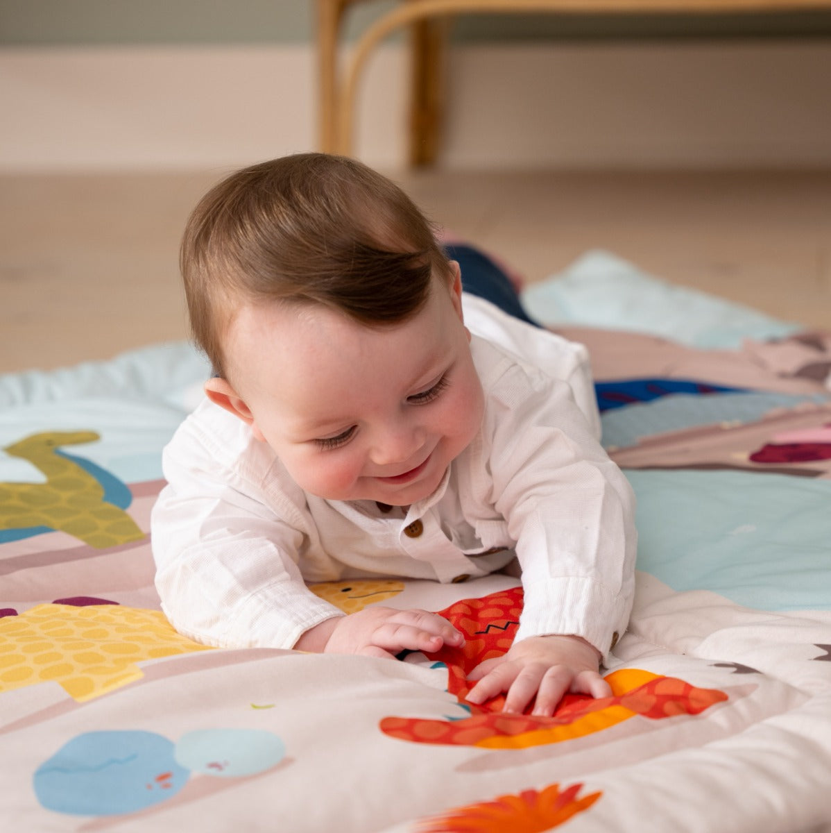 Baby playing on a Patchwork kids reversible playmat in Dino theme in room