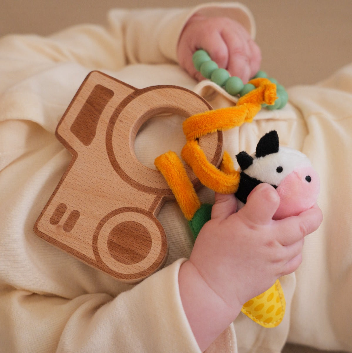 Baby holding Little big friends wooden rattle with farm theme