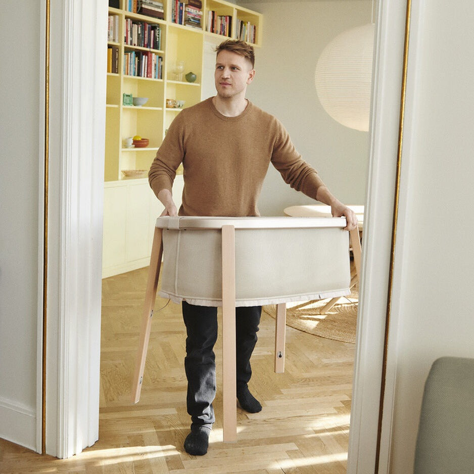Father holding Snoozi baby portable bassinet from Stokke