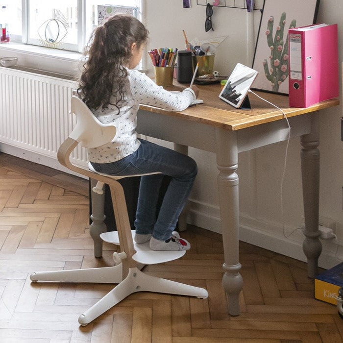 Nomi Natural white highchair from Stokke studying in a room