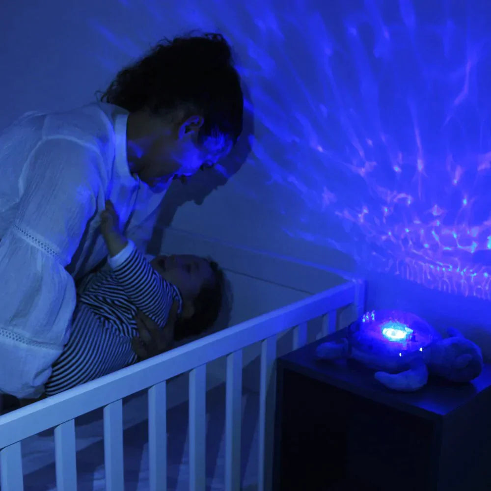 Mother putting baby to bed with Cloud.b Tranquil Turtle pink