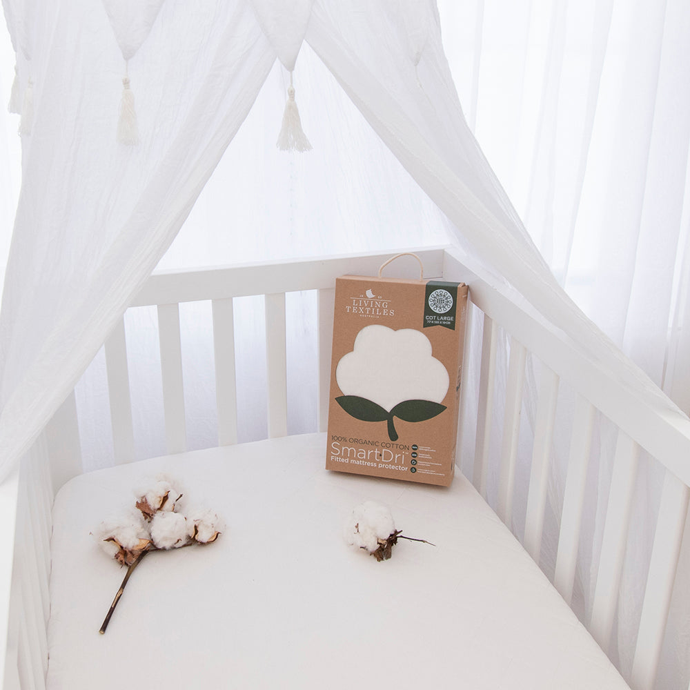 Organic Smart Dri Mattress Protector by Living Textiles packaging and places in a cot.