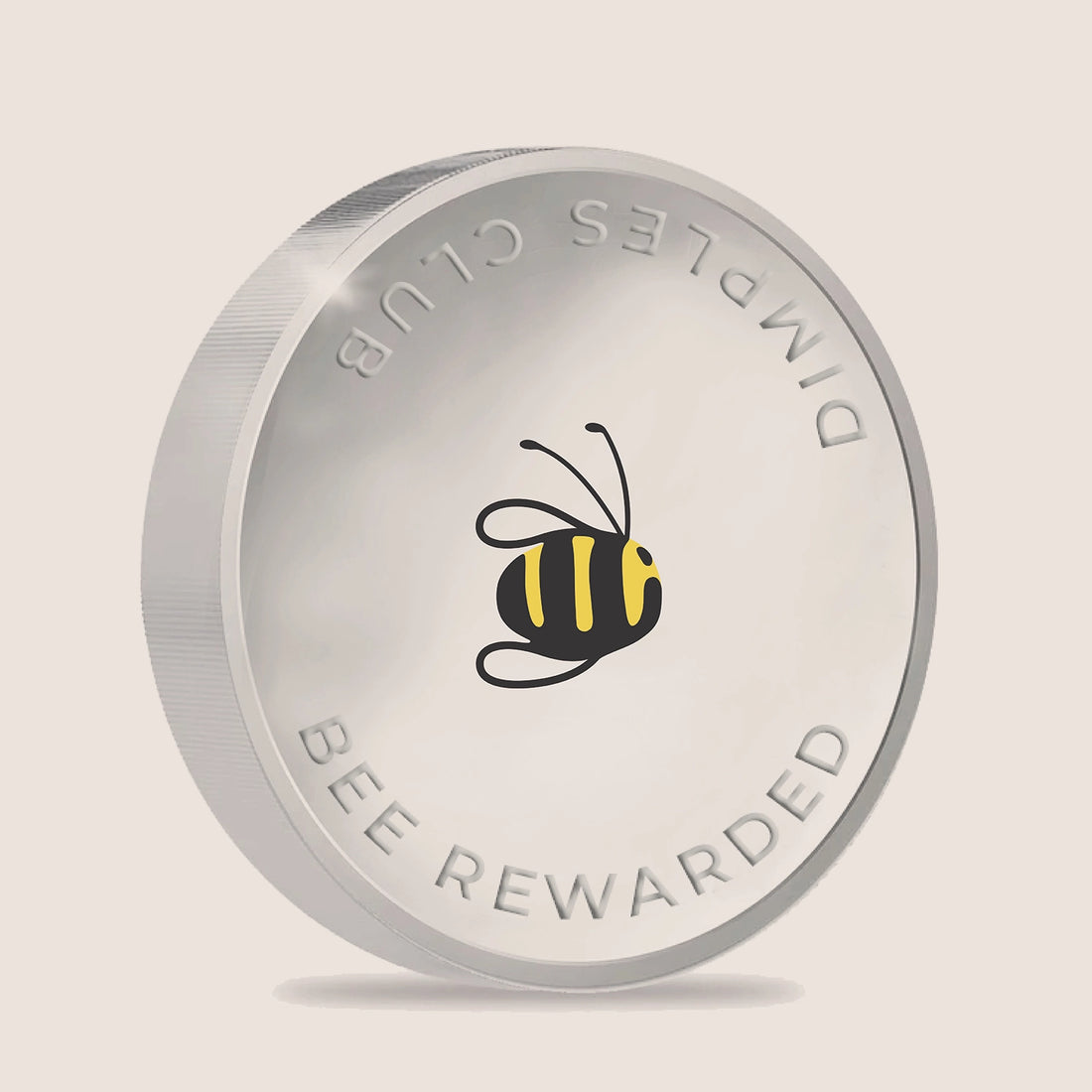 Silver coin with bee design and 'Dimples Club' text on a beige background