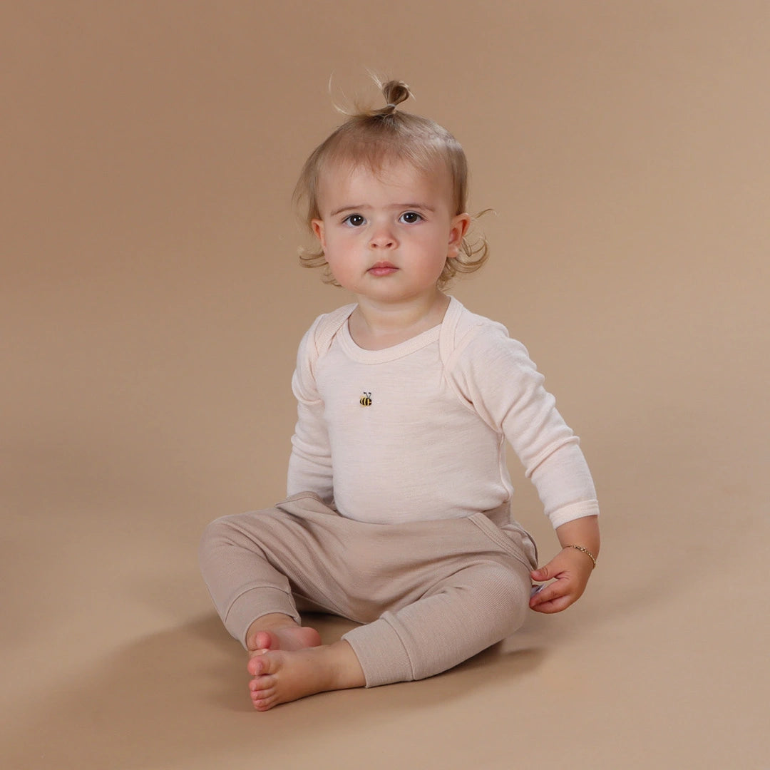 Baby girl sitting wearing dimples merino bodysuit and pants