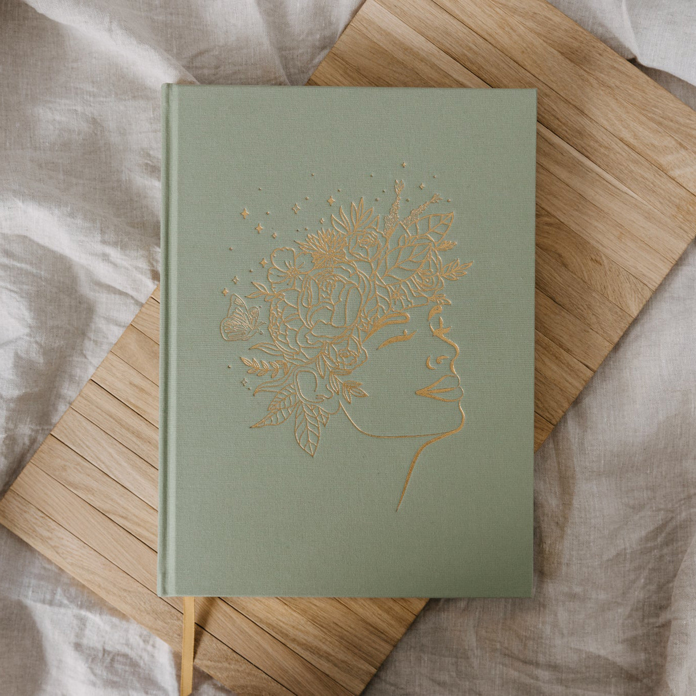 Green notebook with gold embossed design on a wooden surface