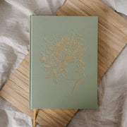 Green notebook with gold embossed design on a wooden surface