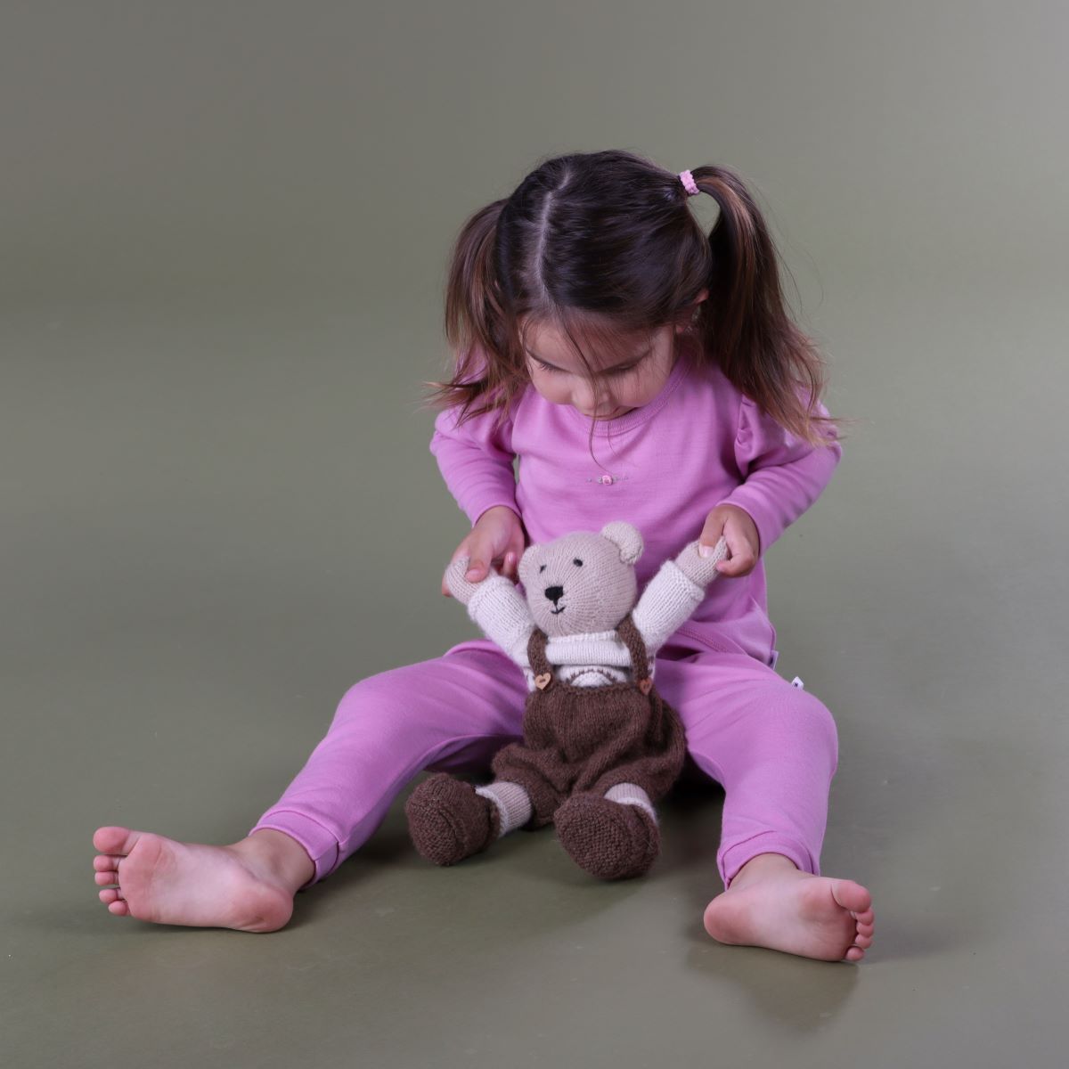 Baby firl sitting and playing wearing merino puff sleeve top paiting it with leggings in orchid colour