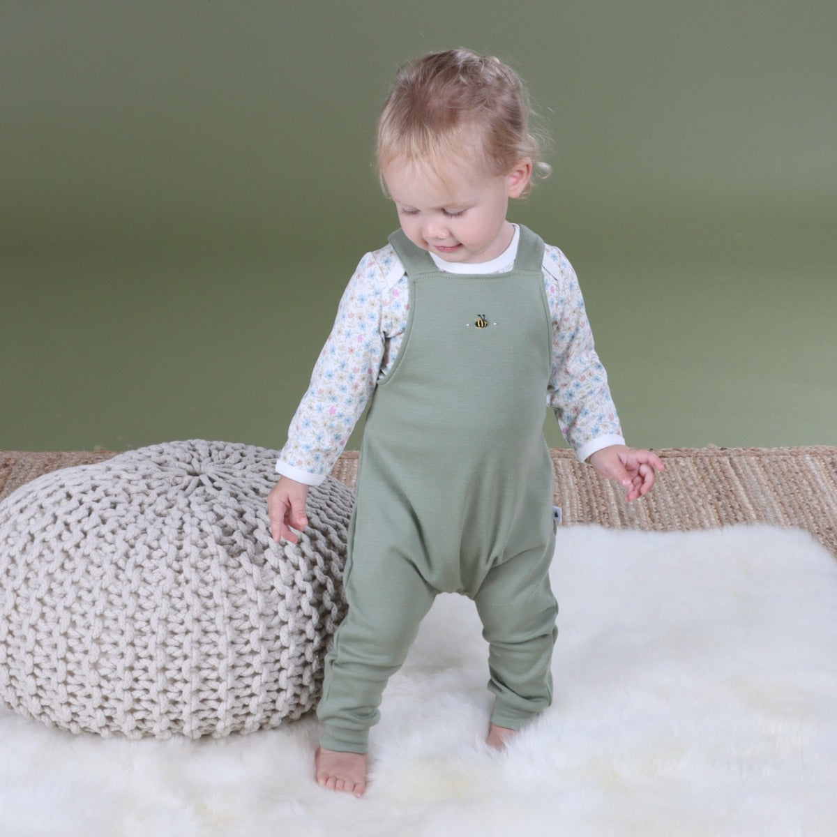 Baby wearing Arctic Adventure Merino Overall in Moss pairing it with floral sleeve top