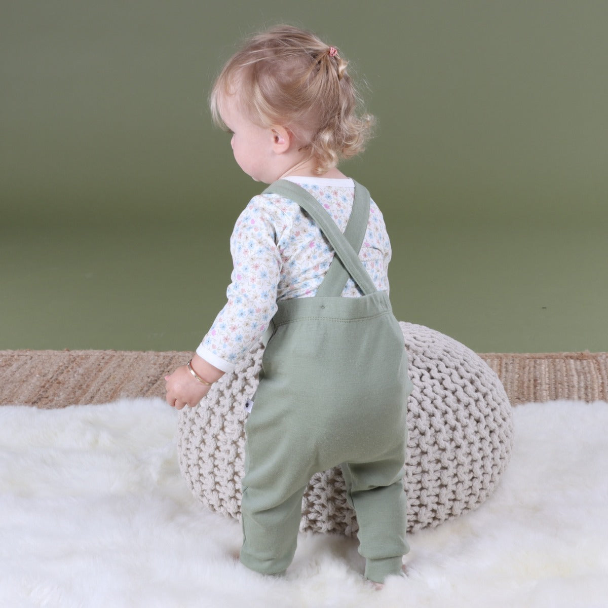 Baby wearing Arctic Adventure Merino Overall in Moss pairing it with floral sleeve top