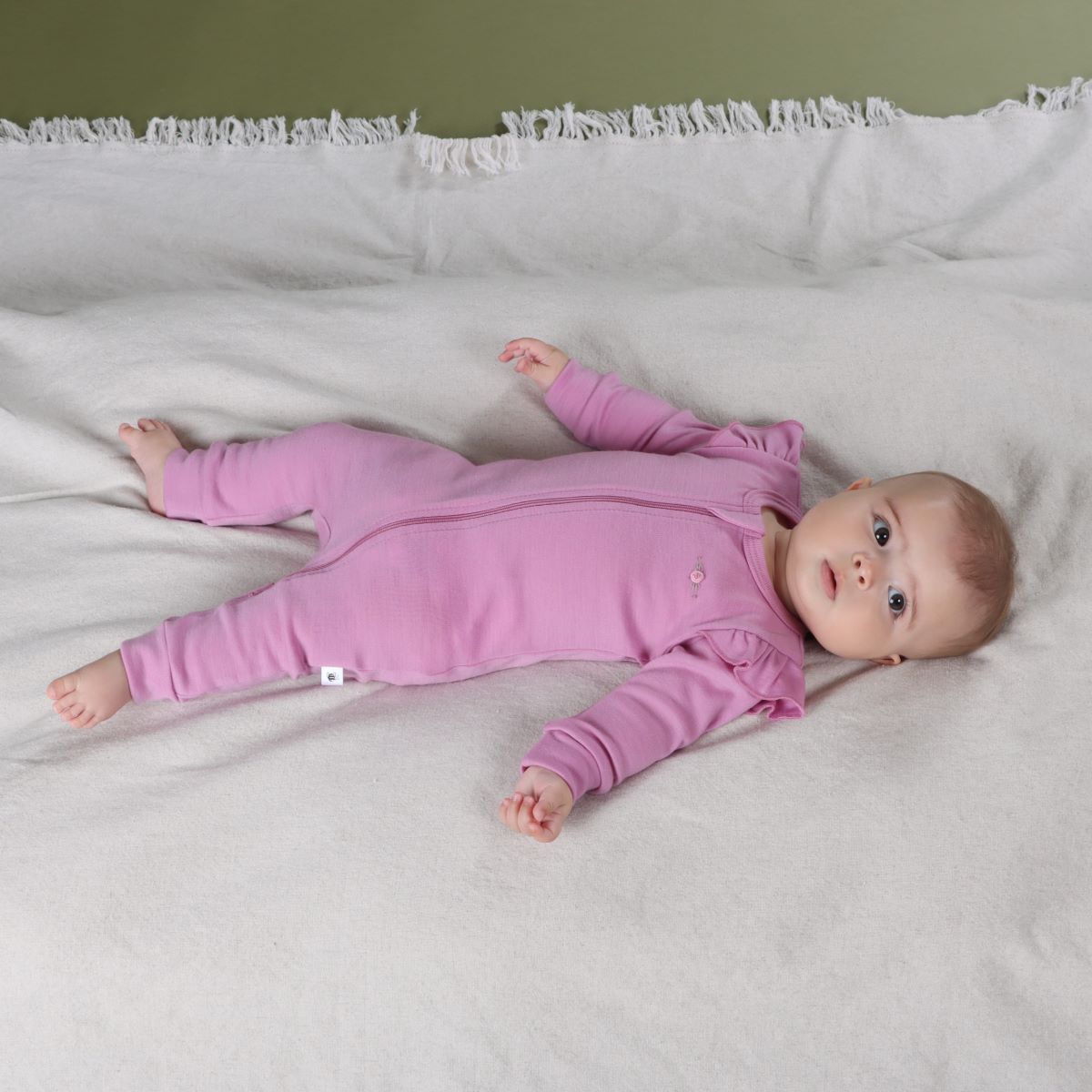 Baby girl sleeping wearing Orchid Merino Frill Zip Baby grow