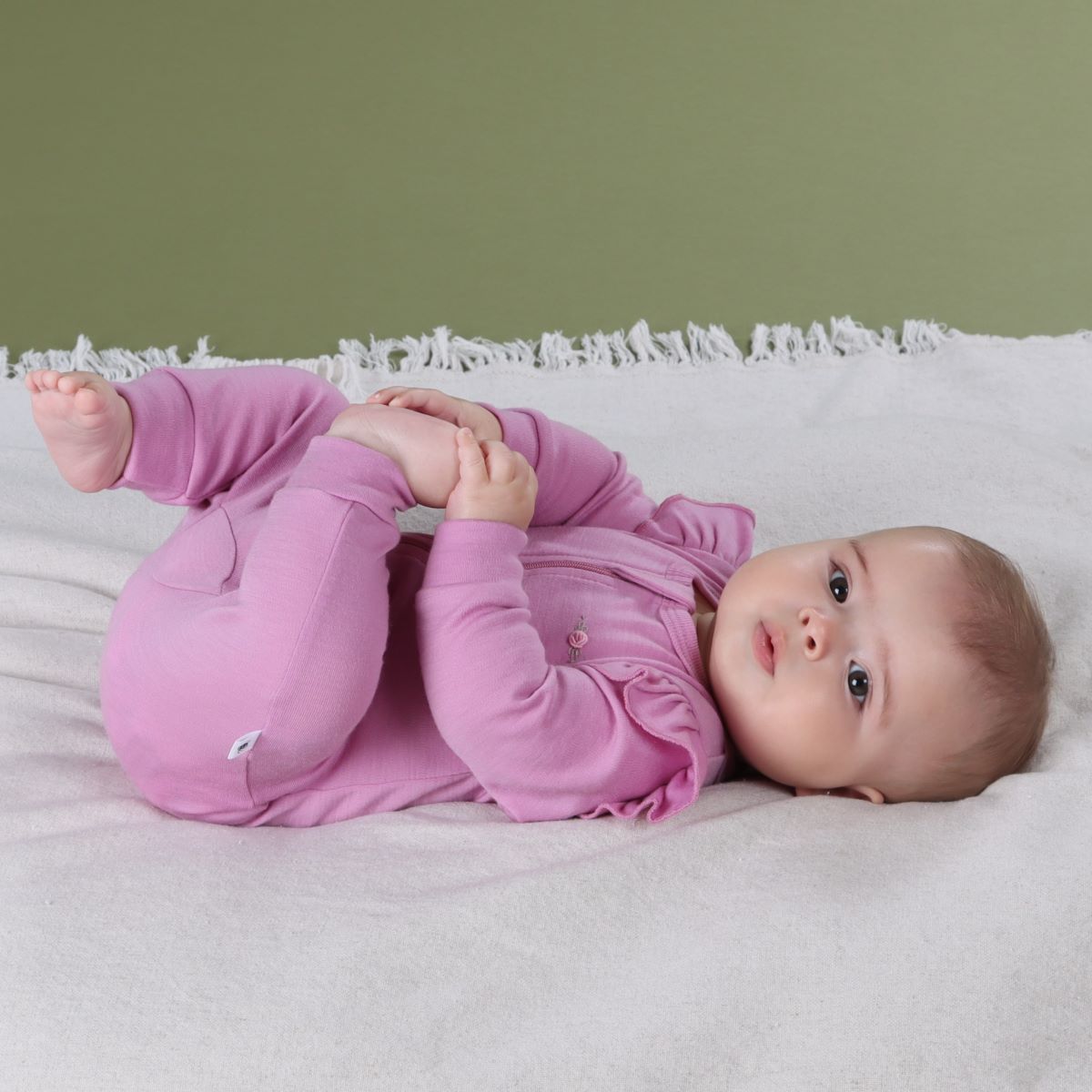 Baby girl sleeping wearing Orchid Merino Frill Zip Baby grow