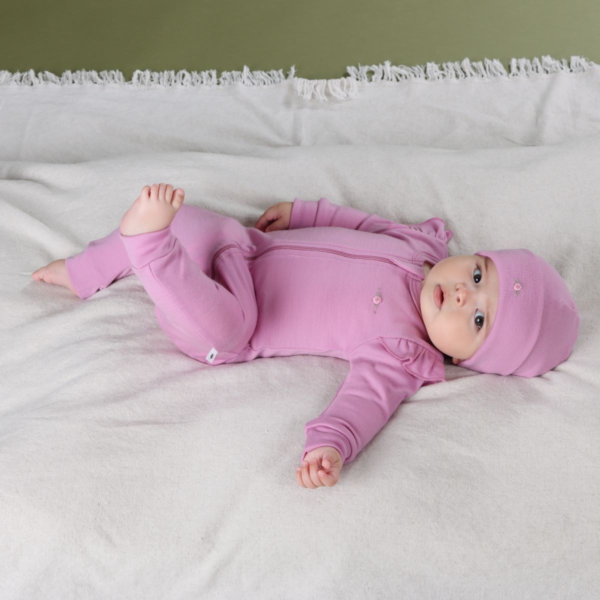 Baby girl sleeping wearing Orchid Merino Frill Zip Baby grow