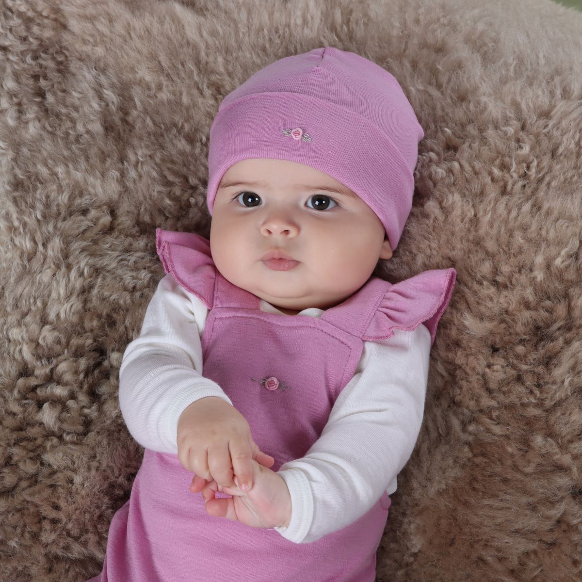 Baby girl wearing orchid merino beanie pairing it with merino body suit and frill overall from arctic adventure collection