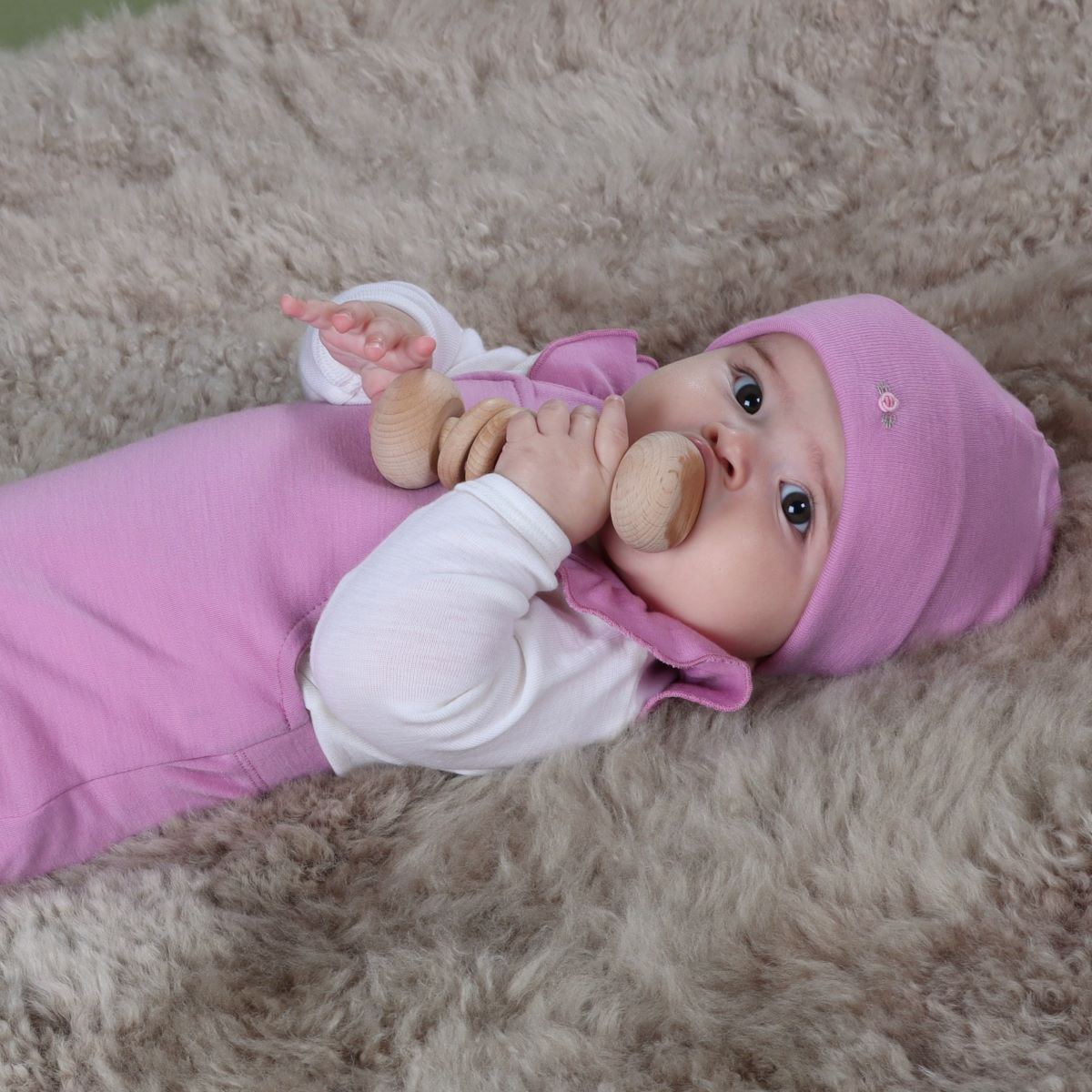 
Baby girl wearing orchid merino beanie pairing it with merino body suit and frill overall from arctic adventure collection
