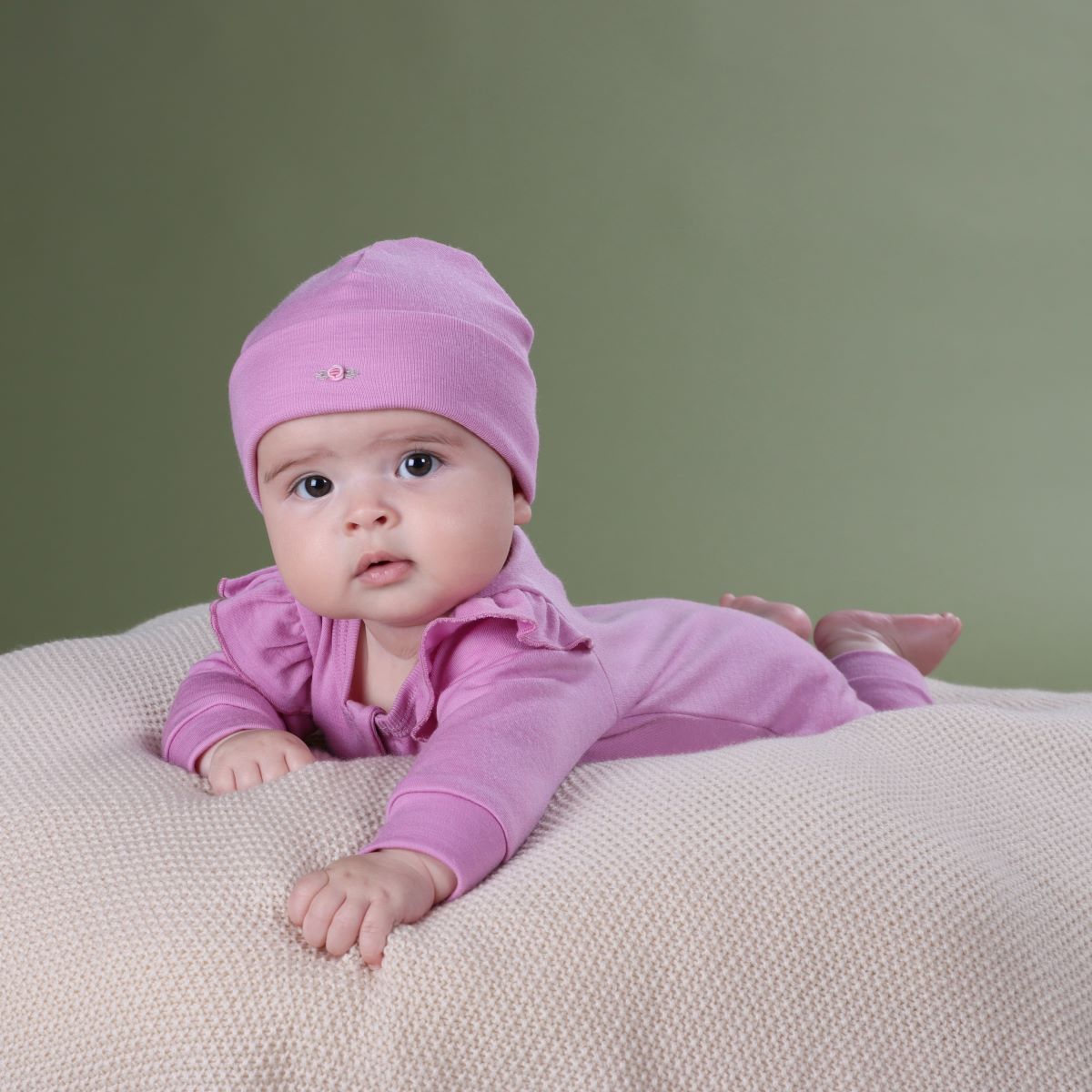 
Baby girl wearing orchid merino beanie pairing it with merino frill body suit from arctic adventure collection 
