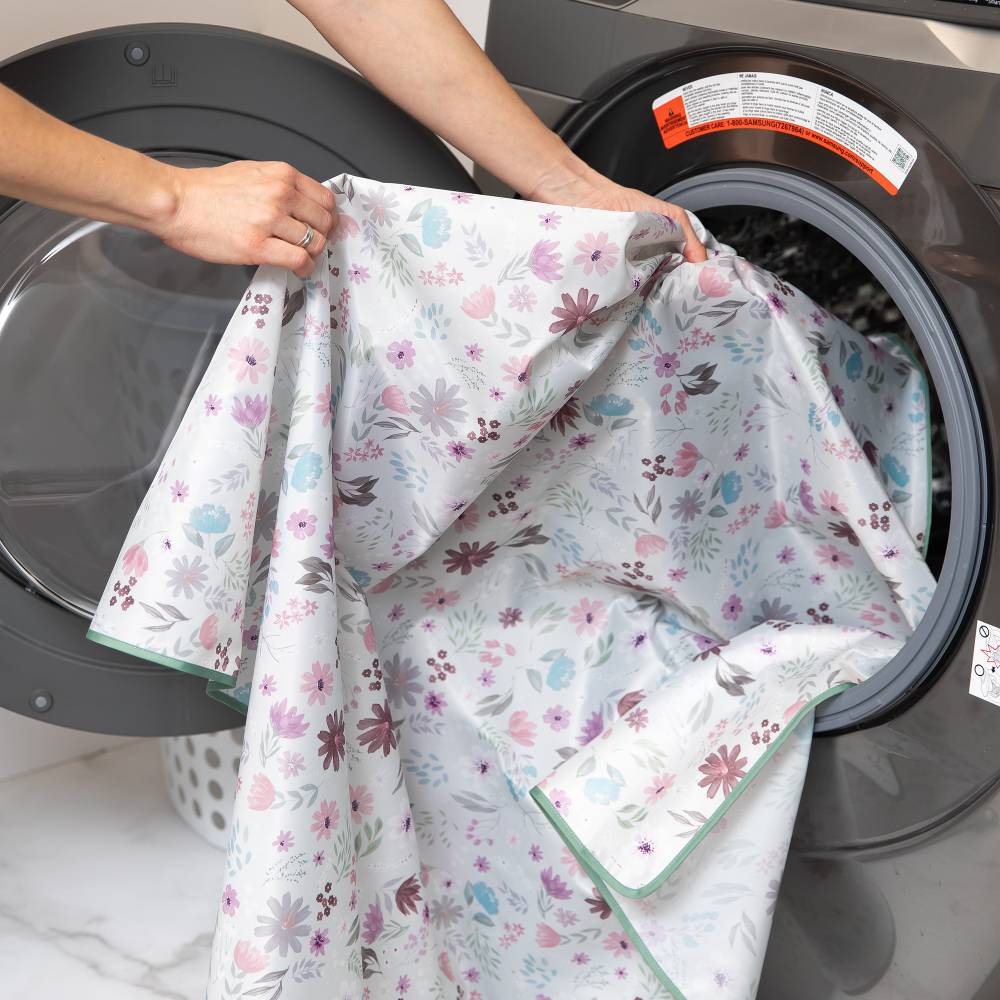 Lady taking out the floral summer vibes waterproof splat mat from Bumkins from a washing machine.
