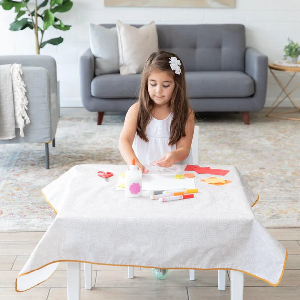 Baby girl playing on table in Wander waterproof splat mat by bumkins.