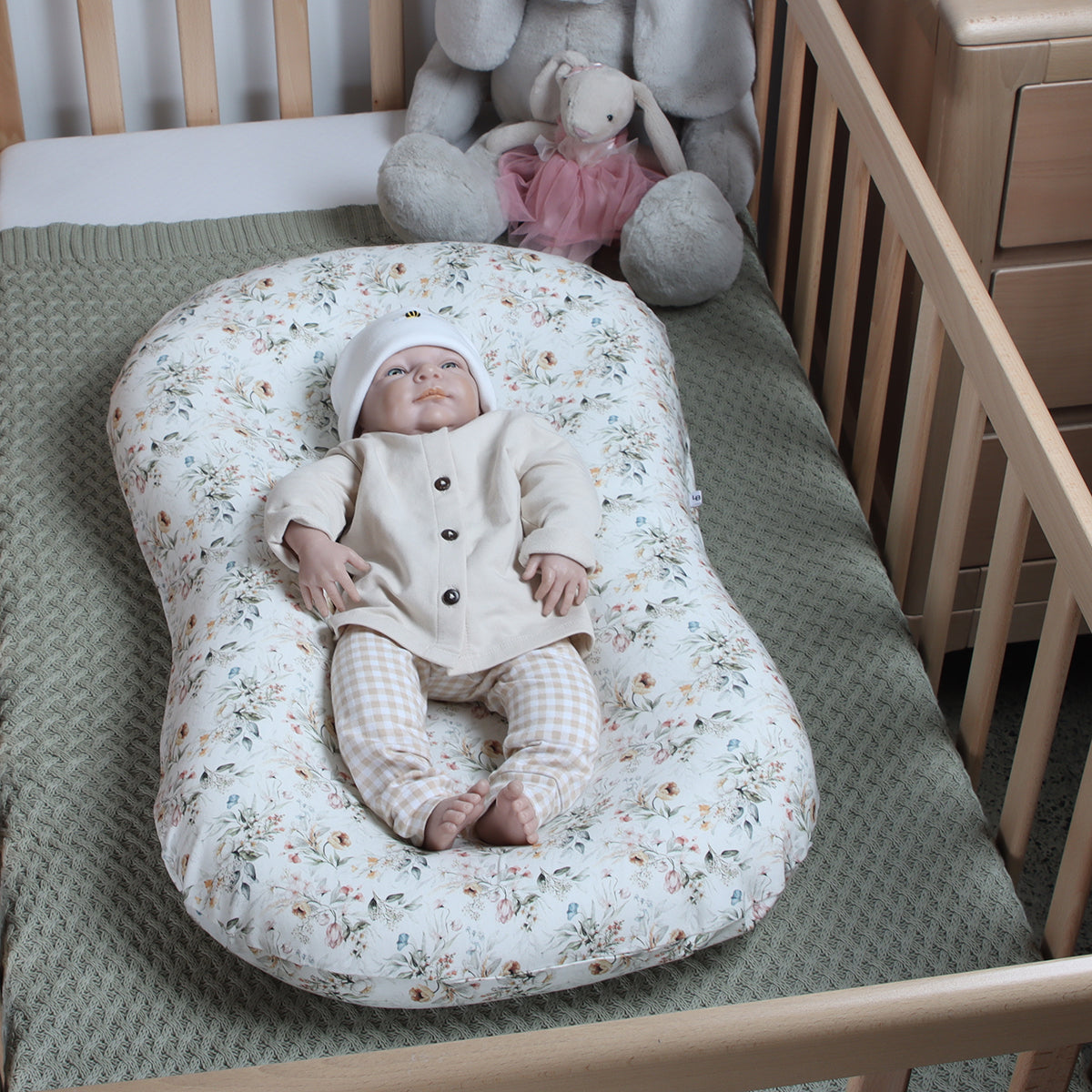 Baby in Lounger in a cot with floral lounger cover