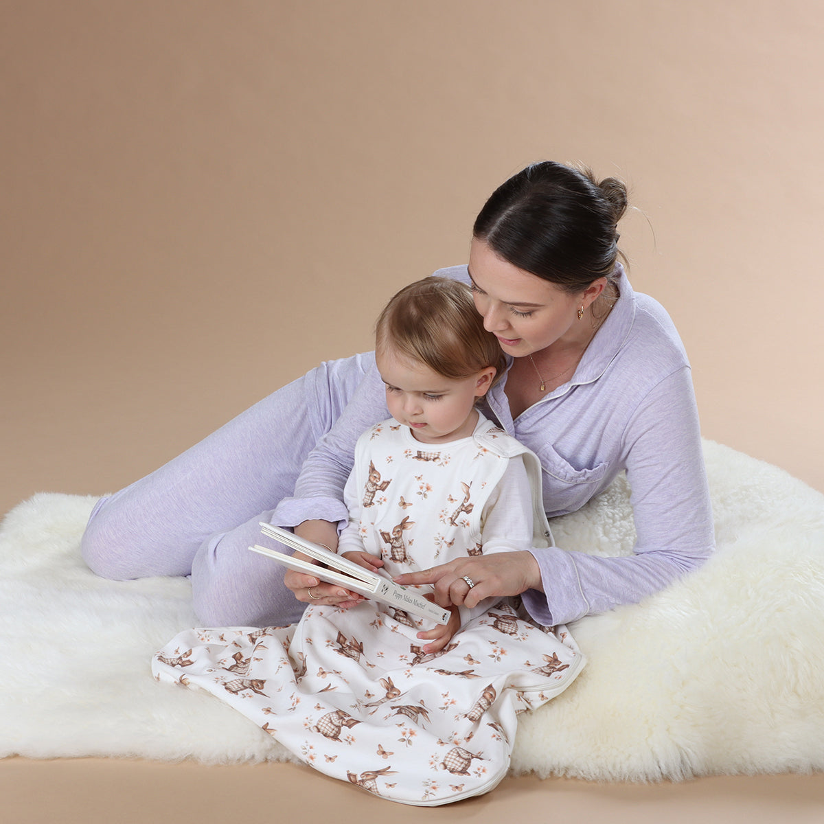 Mother reading book to baby girl wearing All season merino/cotton sleeping bag with bunny book print