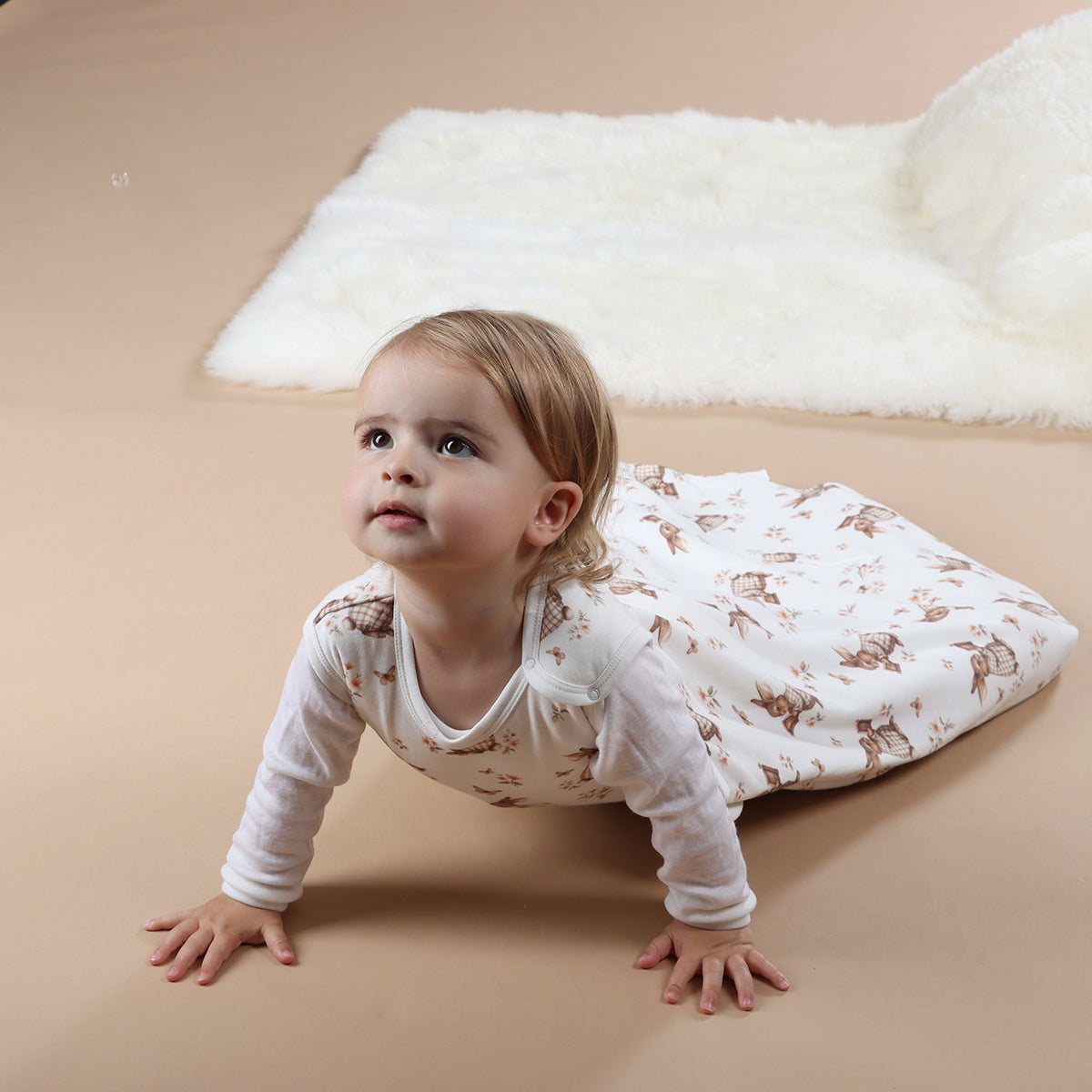 Baby girl crawling wearing All season merino/cotton sleeping bag with bunny book print