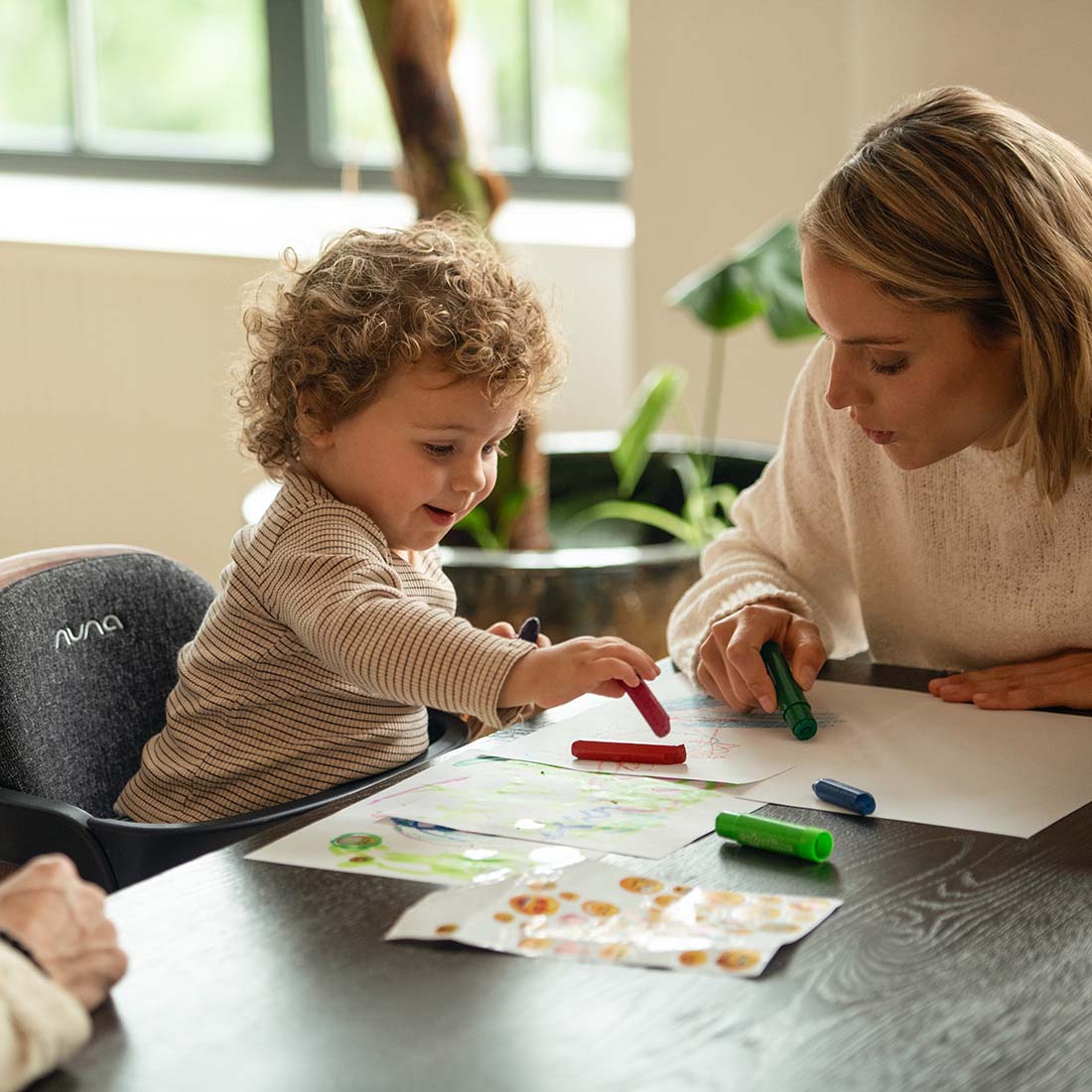 Baby on Bryn highchair playing coloring with mother