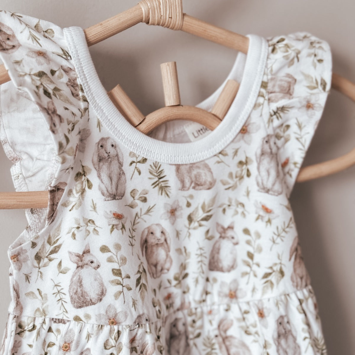 Little bee cotton tiered dress in white with bunny print on a hanger