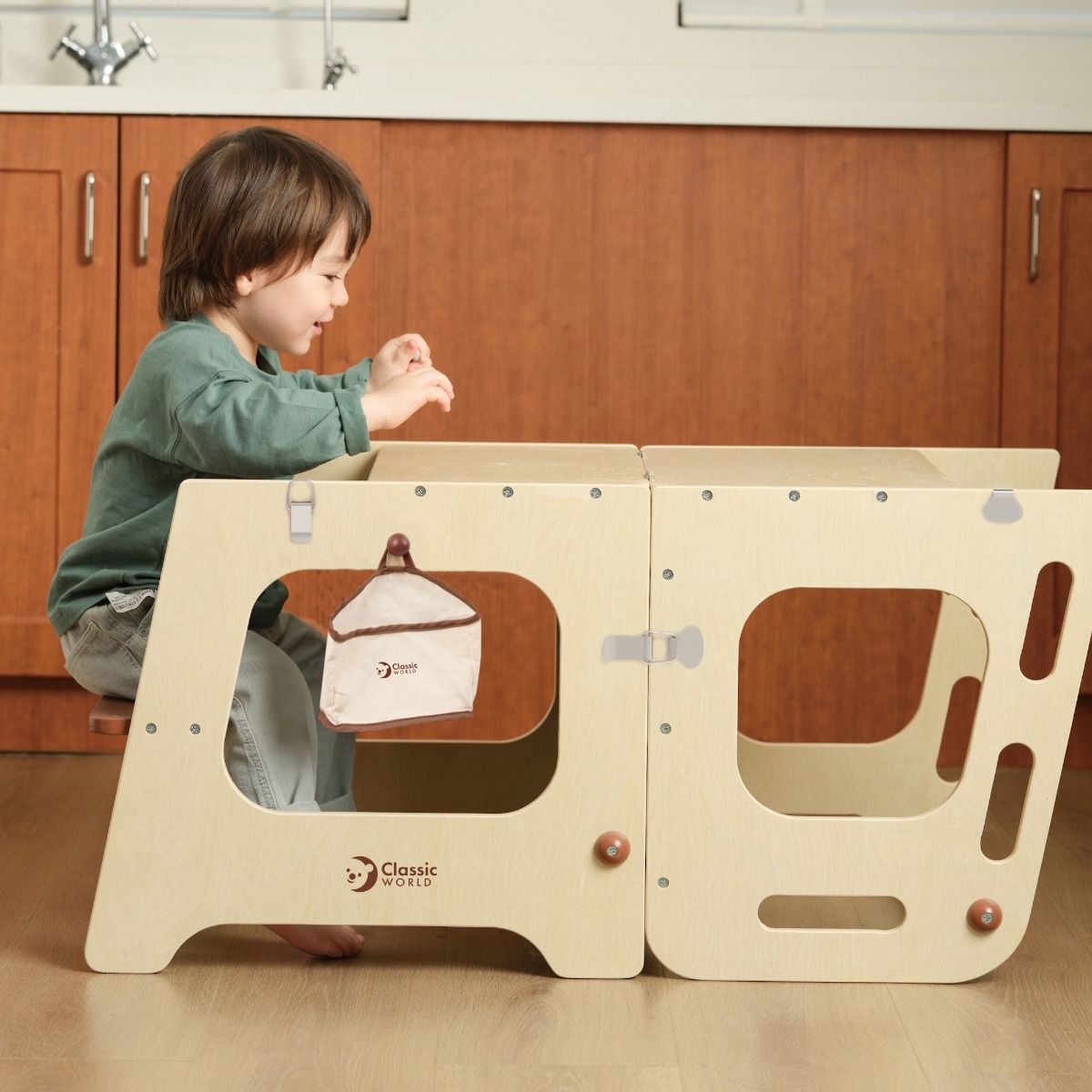 Boy sitting on Wooden convertible tower and table for kids play