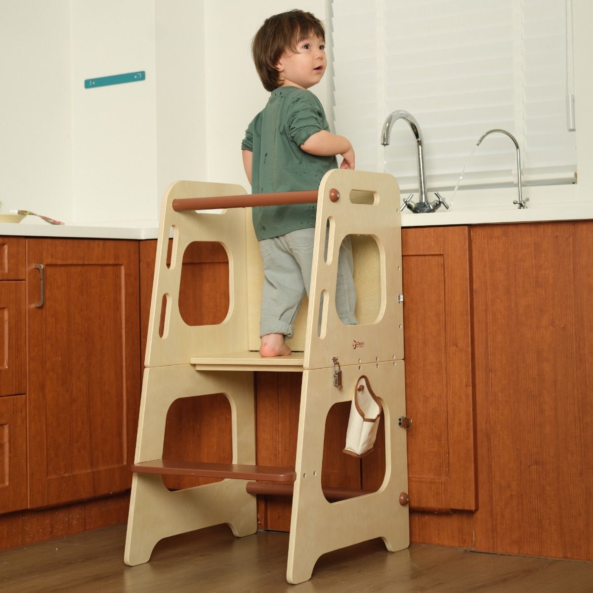 Boy standing on Wooden convertible tower and table in kitchen