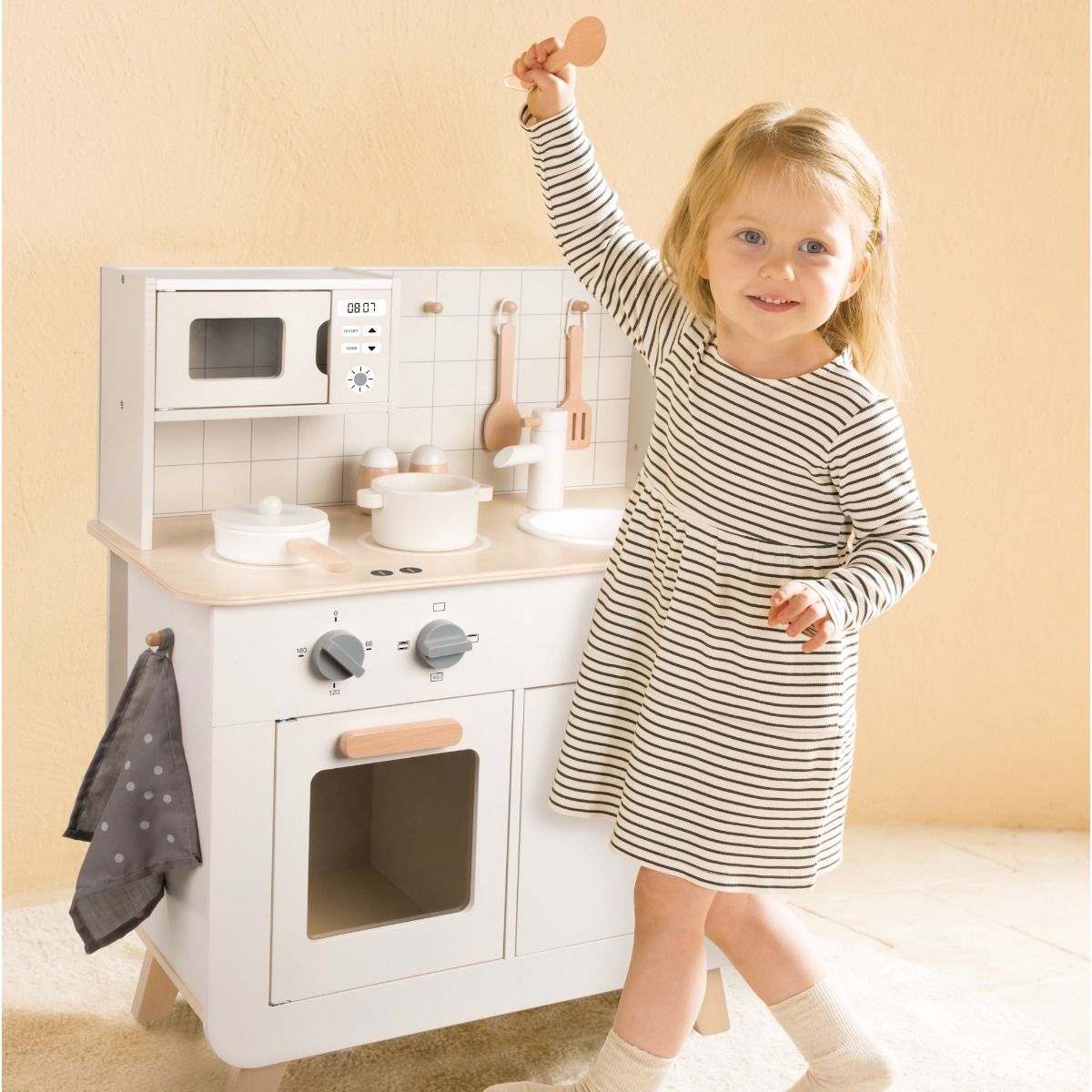 Girl playing with Wooden kitchen play set with all accessories