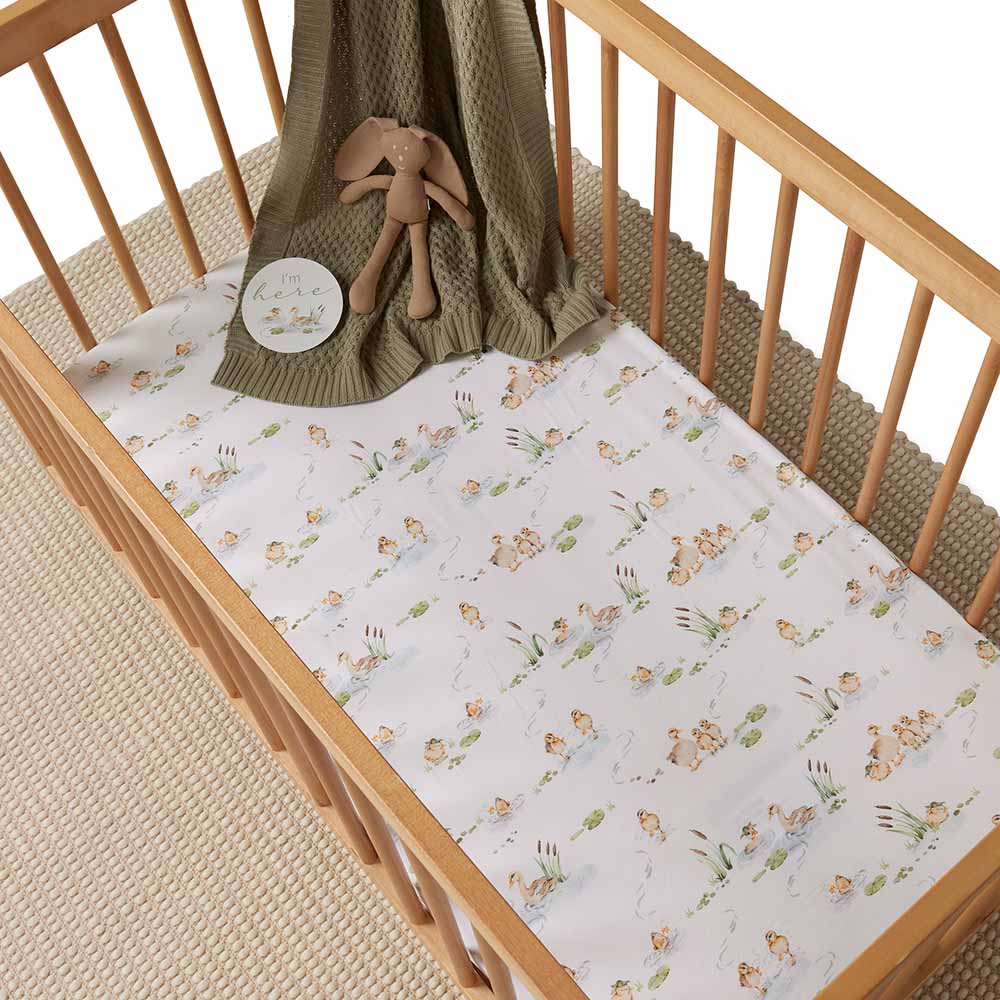 Duck Pond print Snuggle Hunny Organic kids cot sheet in a cot with knit blanket