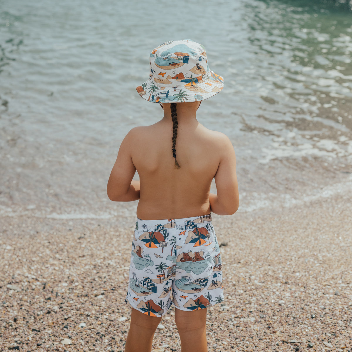 Boy wearing Crywolf Board Shorts with Paradise print back view