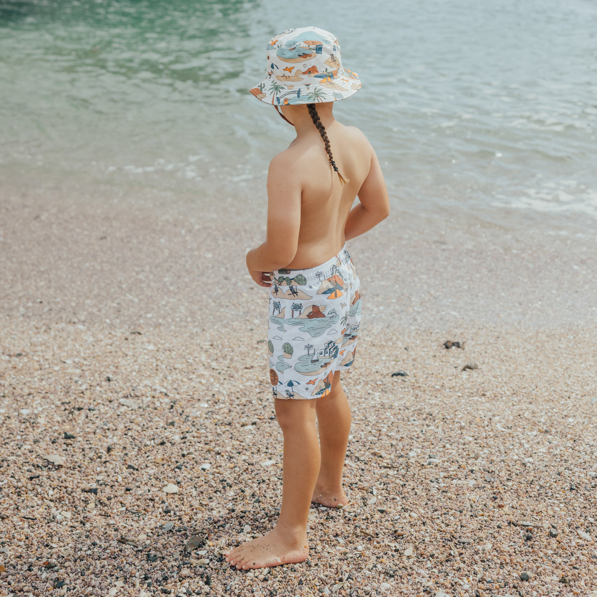 Boy wearing Crywolf Board Shorts with Paradise print on the beach 