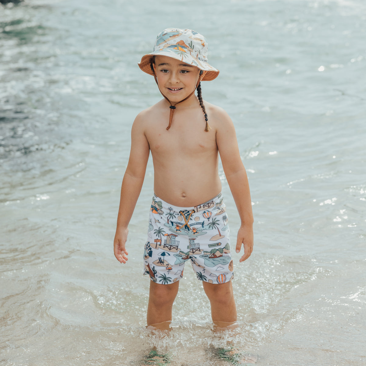 Boy wearing Crywolf Board Shorts with Paradise print in the water