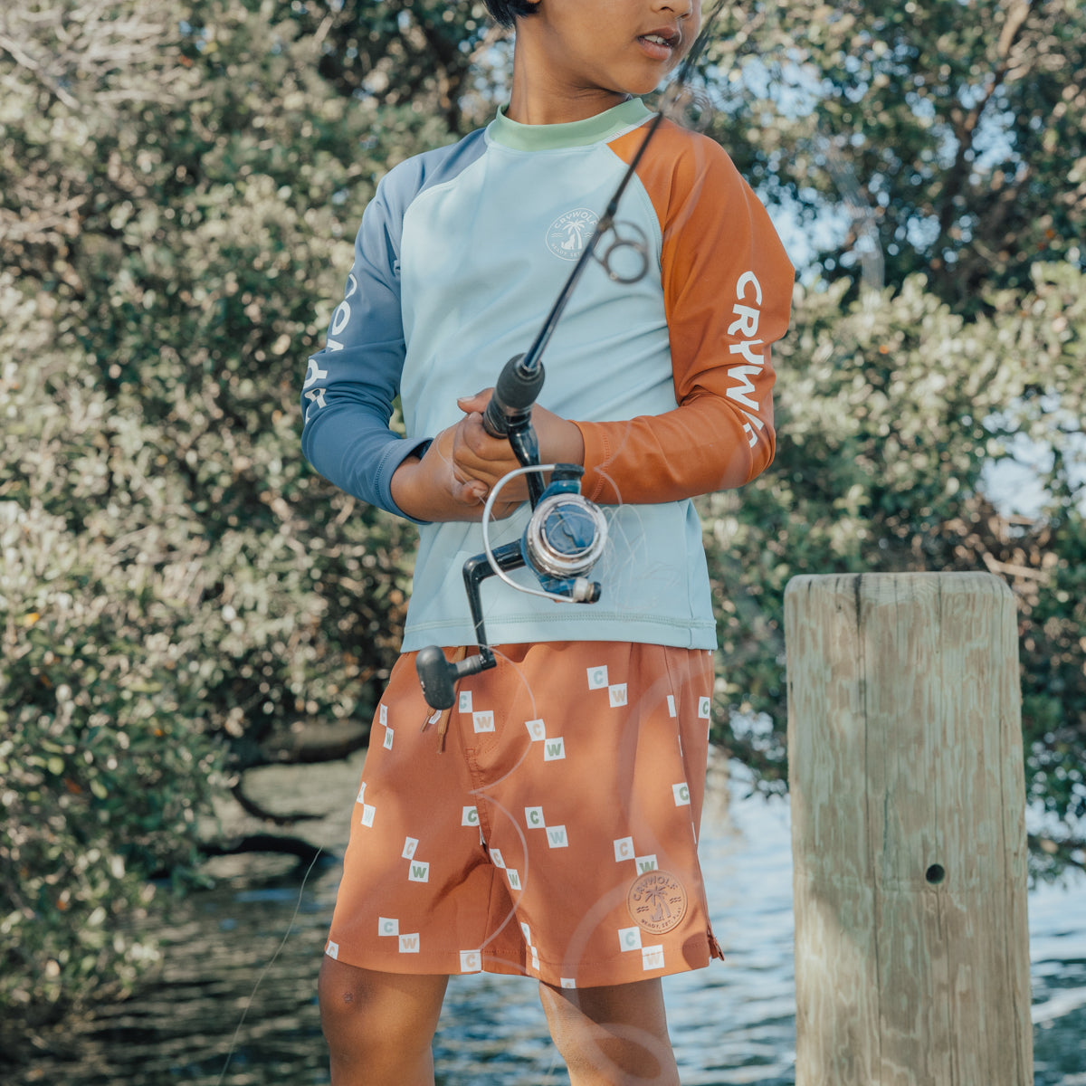Boy fishing while wearing Crywolf Board Shorts with Vacation print