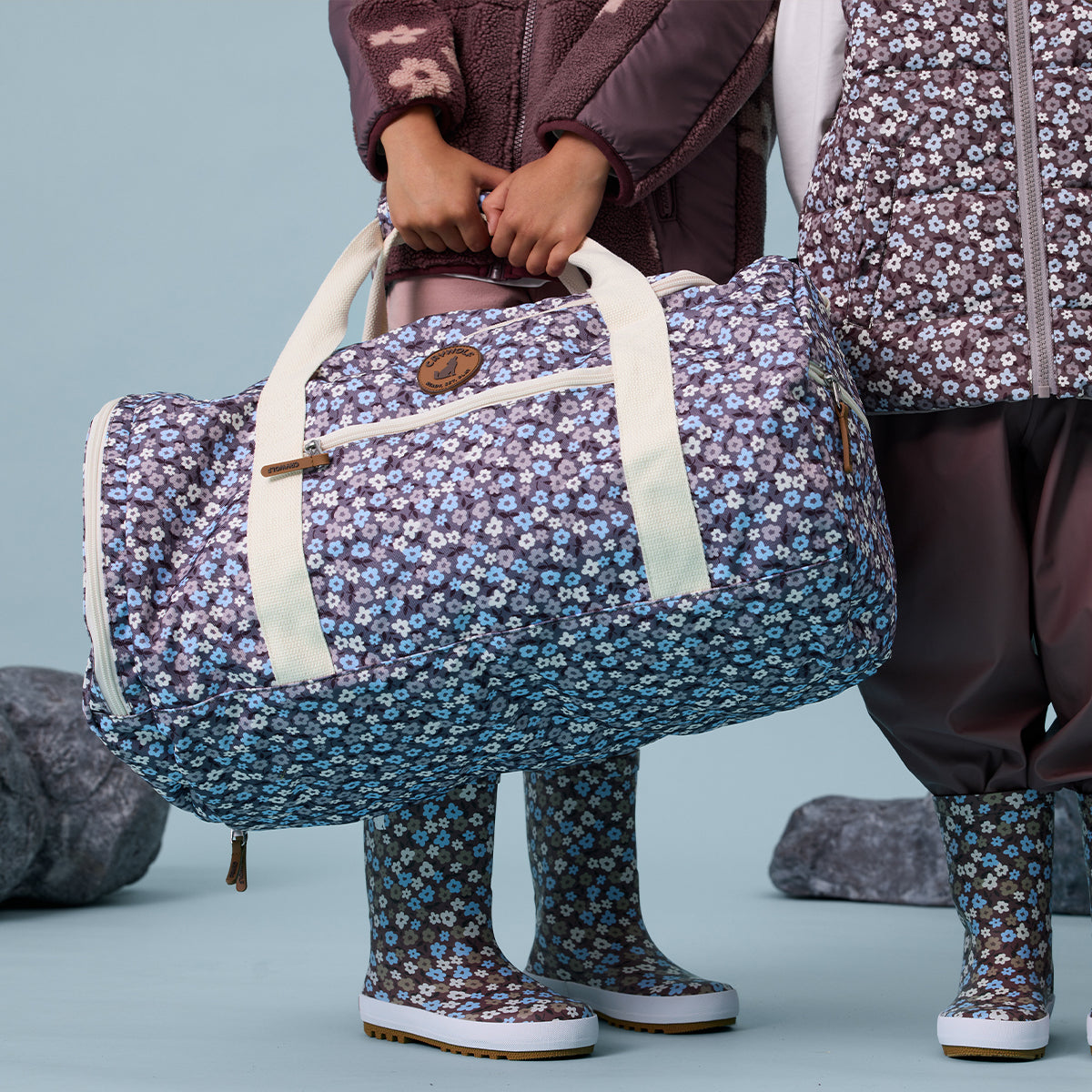 Toddler girl holding floral print recycled duffel bag