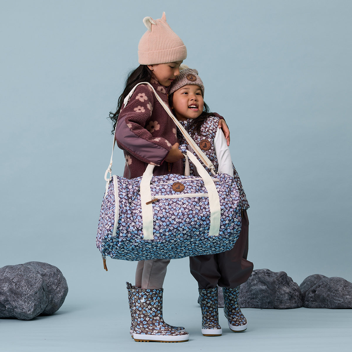 Toddler girl holding floral print recycled duffel bag