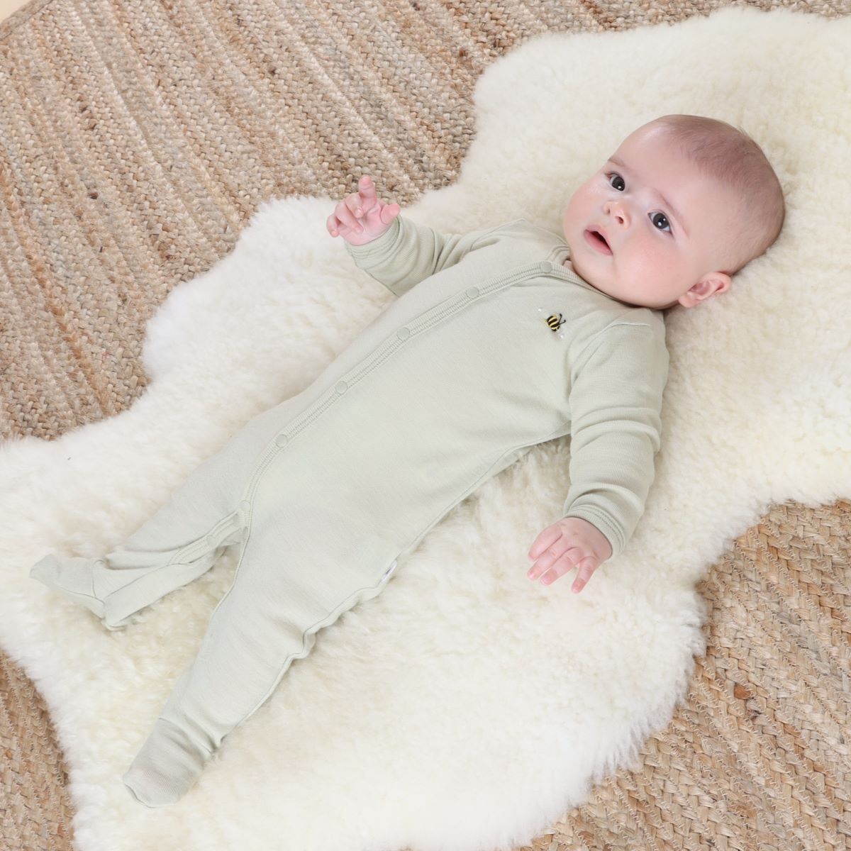 Baby sleeping on a rug wearing Cosy dreams Merino Baby grow in tea green bee from dimples new zealand 