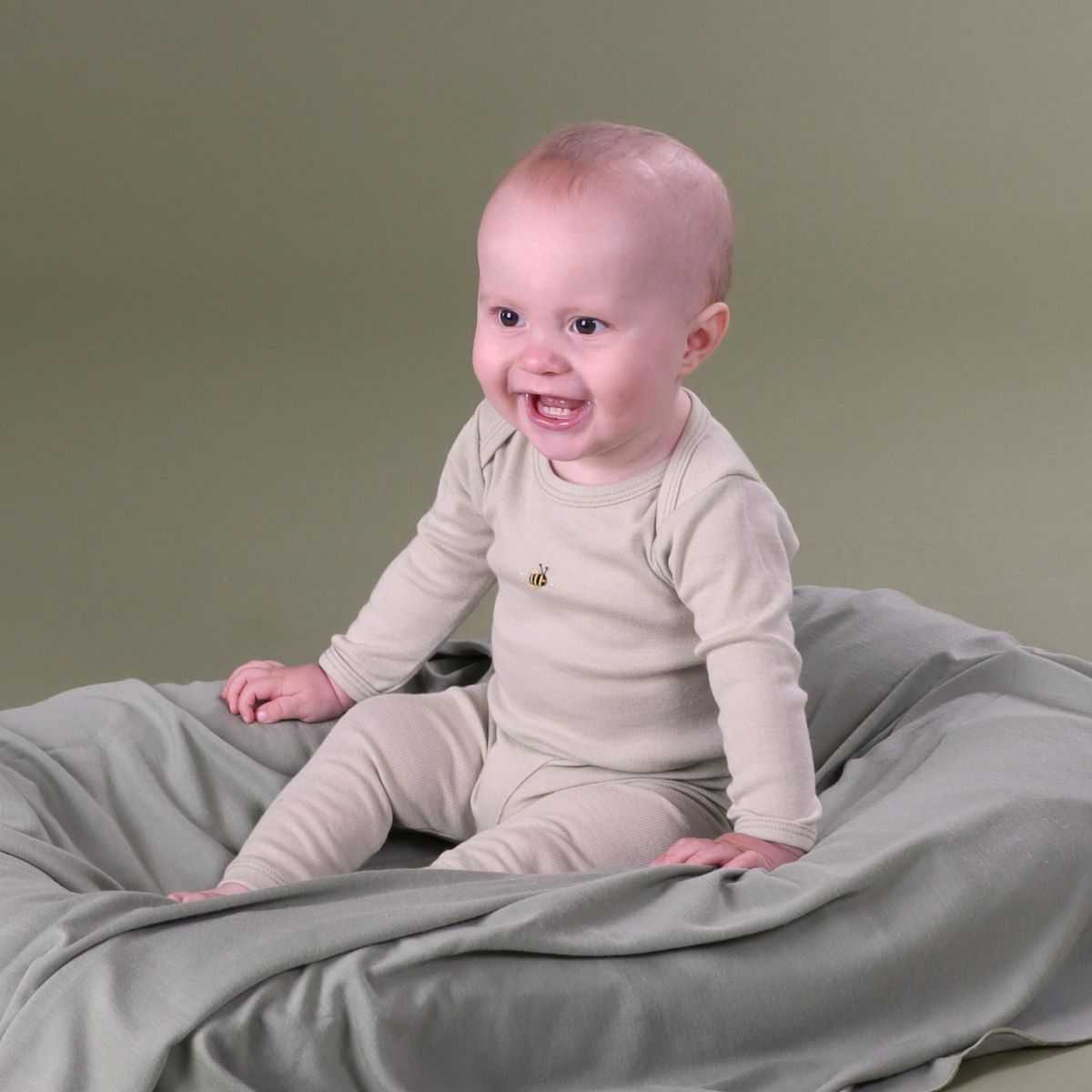 Baby wearing long sleeve onesie front view with bee embroidery pairing it with merino leggings